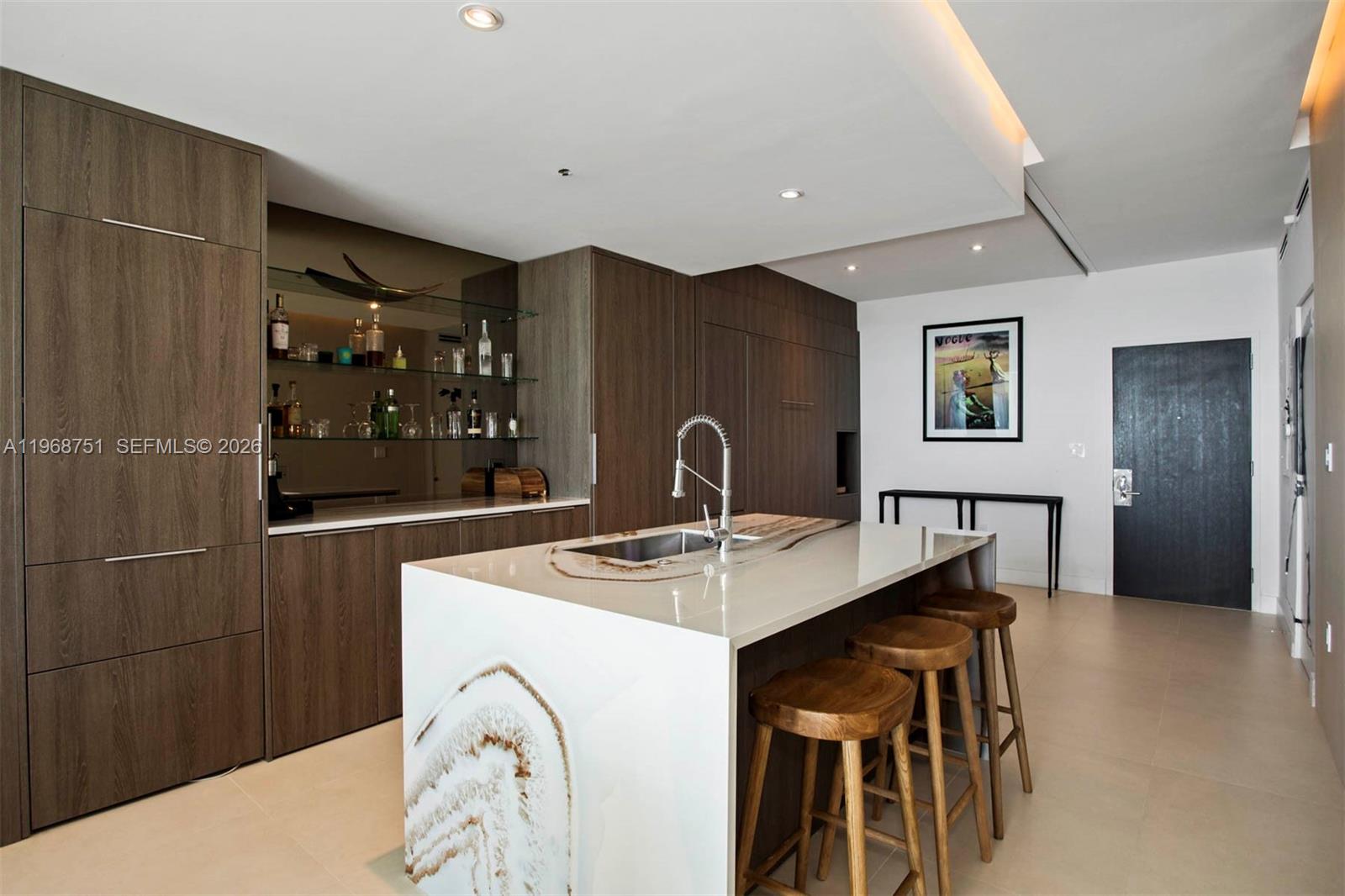 A modern kitchen features dark wood cabinetry, a stone-topped island with stools, and a wet bar — 900 Biscayne Blvd # 4307, Miami FL 33132, MIAMI, FL