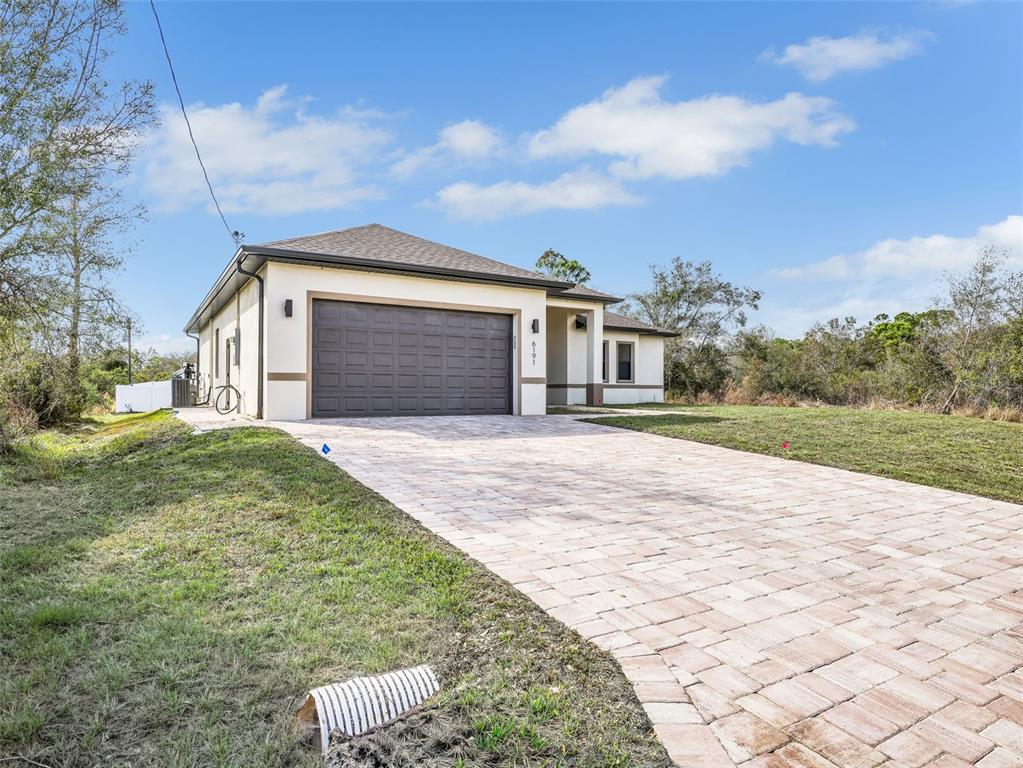 A single-story house with a paved driveway, a dark garage door, and a light-colored exterior — 6191 KAMBACH STREET, PORT CHARLOTTE, FL
