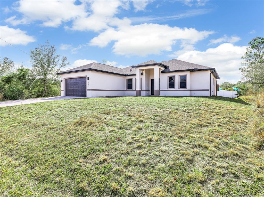 A single-story house with a garage and a large grassy yard under a cloudy sky — 6191 KAMBACH STREET, PORT CHARLOTTE, FL