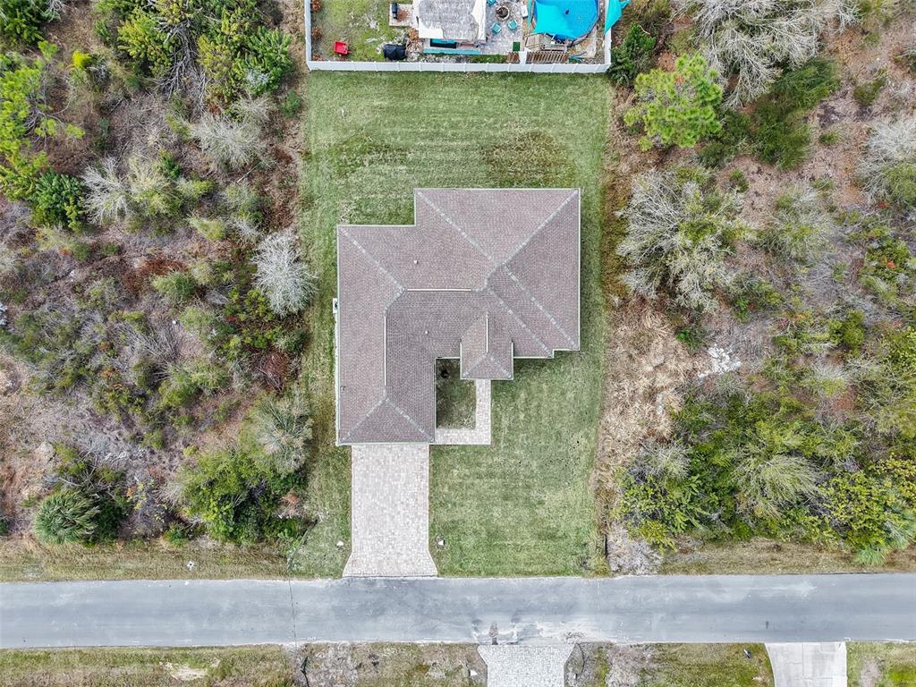 An aerial view shows a single-story house with a paved driveway surrounded by wooded land — 6191 KAMBACH STREET, PORT CHARLOTTE, FL