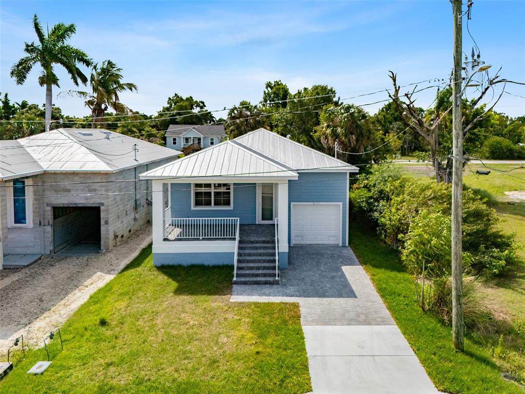 A blue house with a metal roof, front porch, and paved driveway sits on a lawn — 627 FITZHUGH AVENUE, PUNTA GORDA, FL