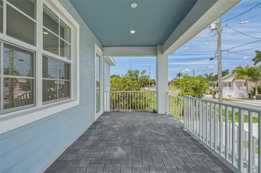 A covered porch features blue siding, a gray paver floor, and white metal railings — 627 FITZHUGH AVENUE, PUNTA GORDA, FL