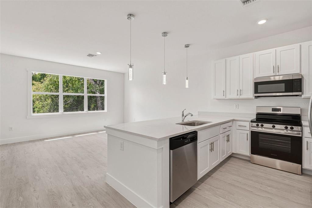A bright kitchen features white cabinets, stainless steel appliances, a center island, and light flooring — 627 FITZHUGH AVENUE, PUNTA GORDA, FL