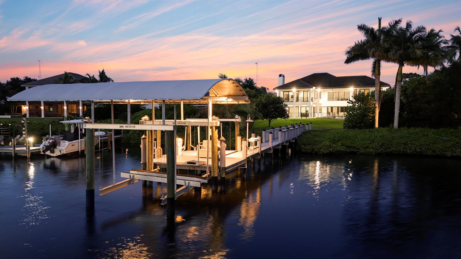 A boat lift and dock extend into a canal in front of a waterfront house — 18411 SE Lakeside Drive, Jupiter FL 33469, JUPITER, FL