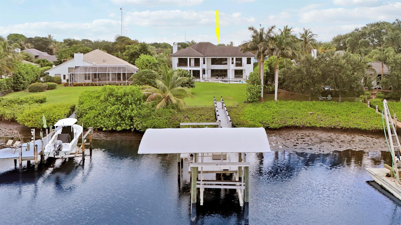An aerial view shows a two-story waterfront house with a private dock and boat lift — 18411 SE Lakeside Drive, Jupiter FL 33469, JUPITER, FL