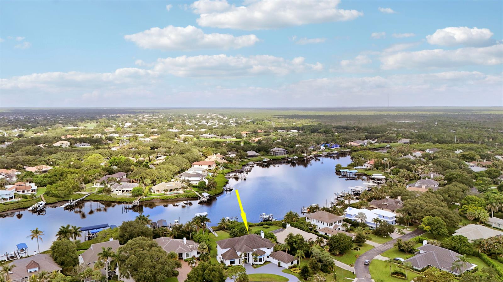 An aerial view shows a waterfront house with a yellow arrow pointing toward it — 18411 SE Lakeside Drive, Jupiter FL 33469, JUPITER, FL