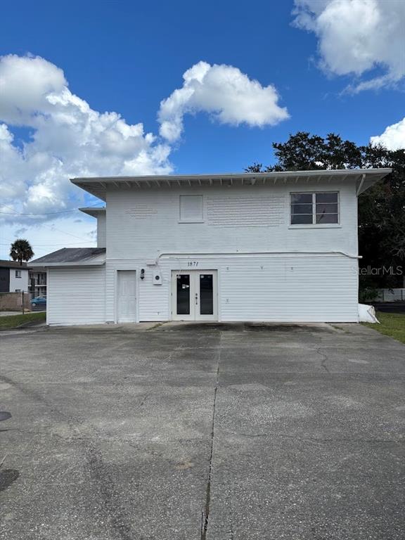 A two-story white building with a concrete parking lot under a blue sky — 1871 S RIDGEWOOD AVENUE, SOUTH DAYTONA, FL