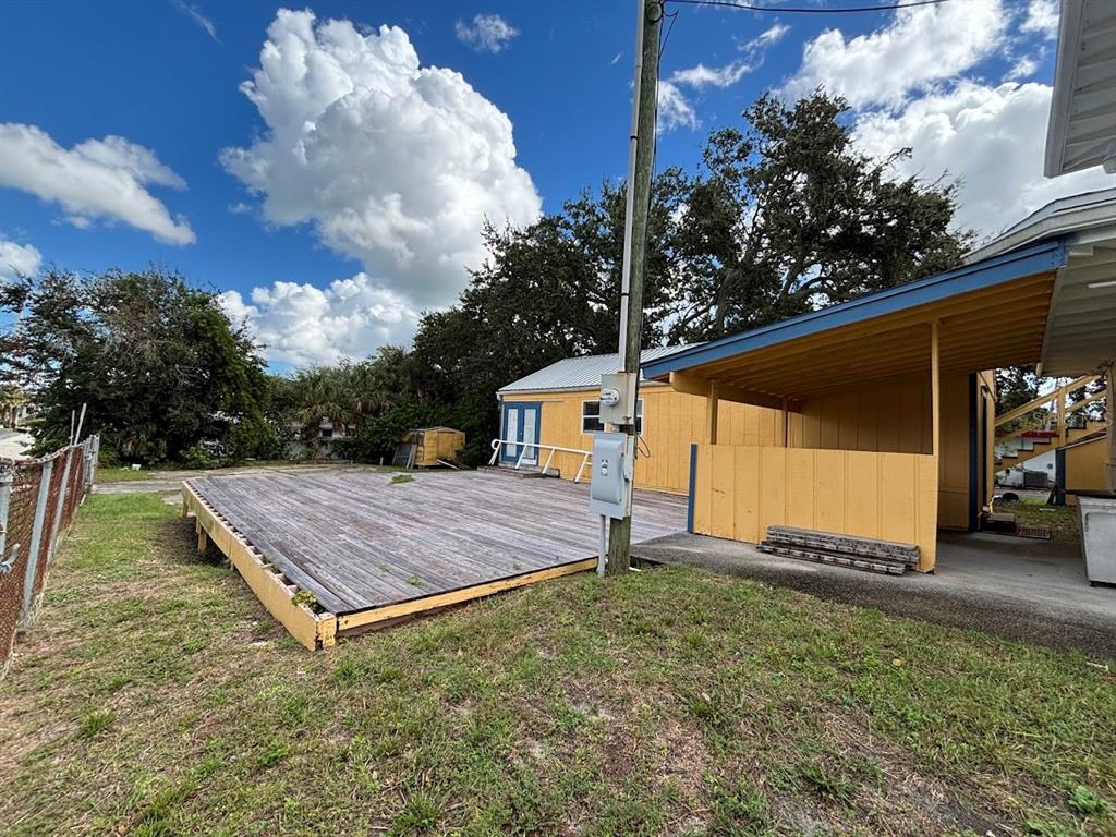 A wooden deck sits in front of a yellow building with a covered carport area — 1871 S RIDGEWOOD AVENUE, SOUTH DAYTONA, FL