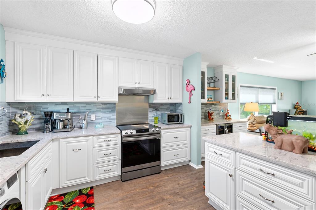 A kitchen with white cabinets, stainless steel appliances, light countertops, and a blue backsplash — 2259 COSTA RICAN DRIVE UNIT 23, CLEARWATER, FL