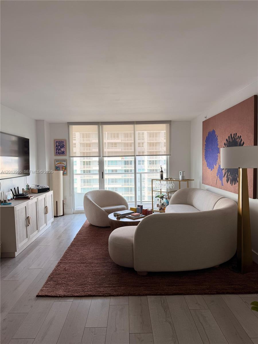 A living room features a curved sofa, a round chair, and a large wall painting — 1155 Brickell Bay Dr # 2904, Miami FL 33131, MIAMI, FL