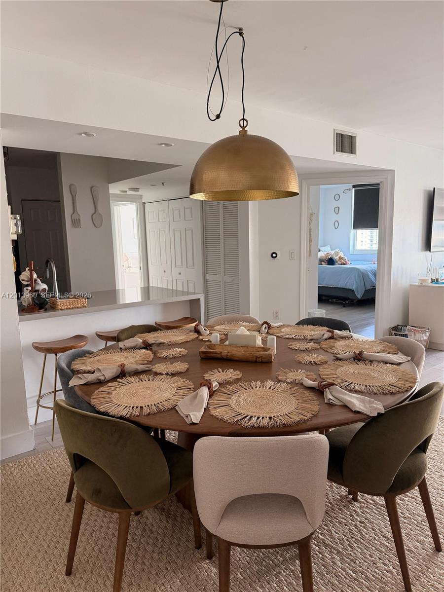 A dining room features a large round wooden table with woven placemats and upholstered chairs — 1155 Brickell Bay Dr # 2904, Miami FL 33131, MIAMI, FL