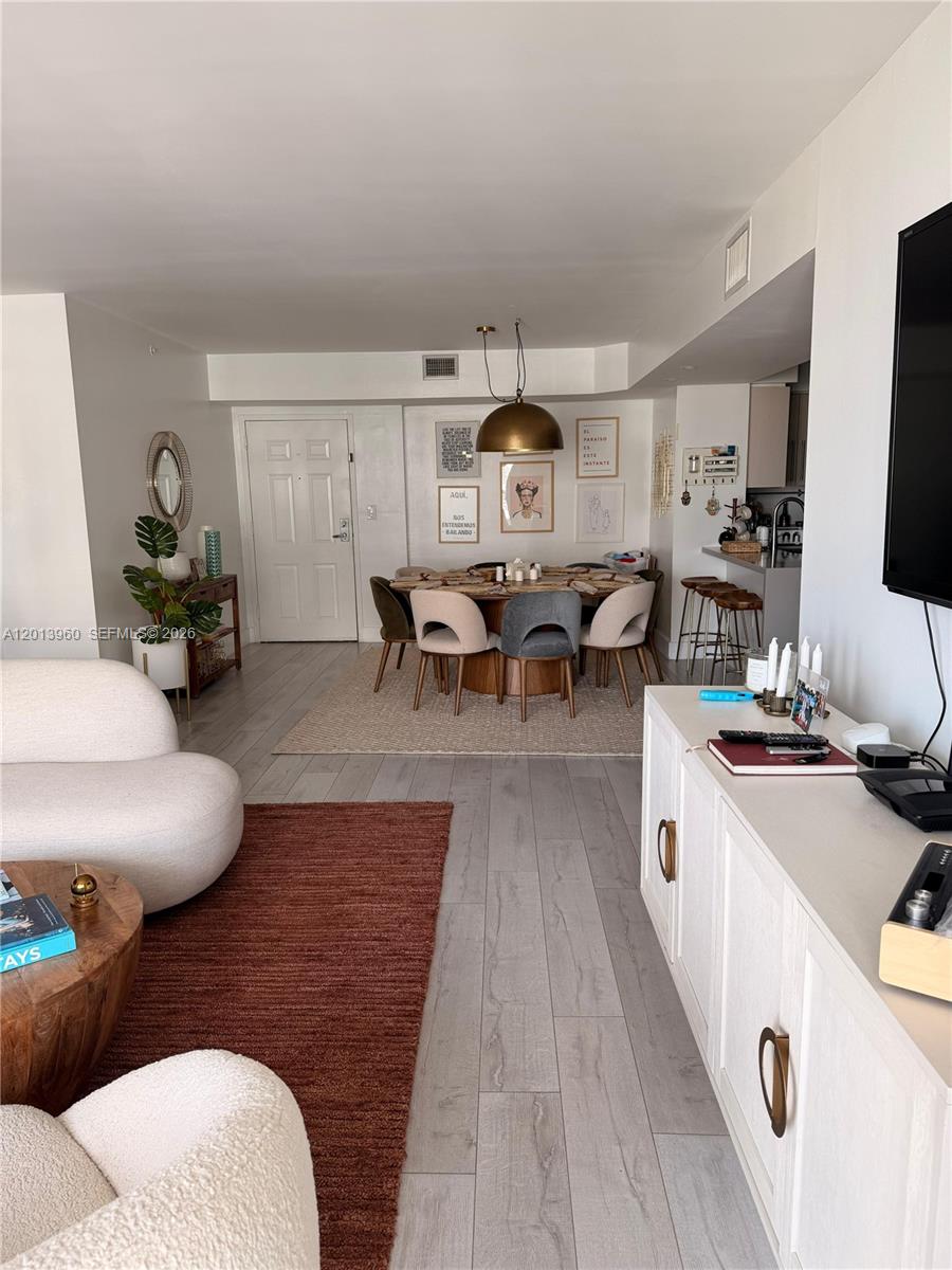 An open-concept living and dining area features light wood flooring, modern furniture, and a round table — 1155 Brickell Bay Dr # 2904, Miami FL 33131, MIAMI, FL