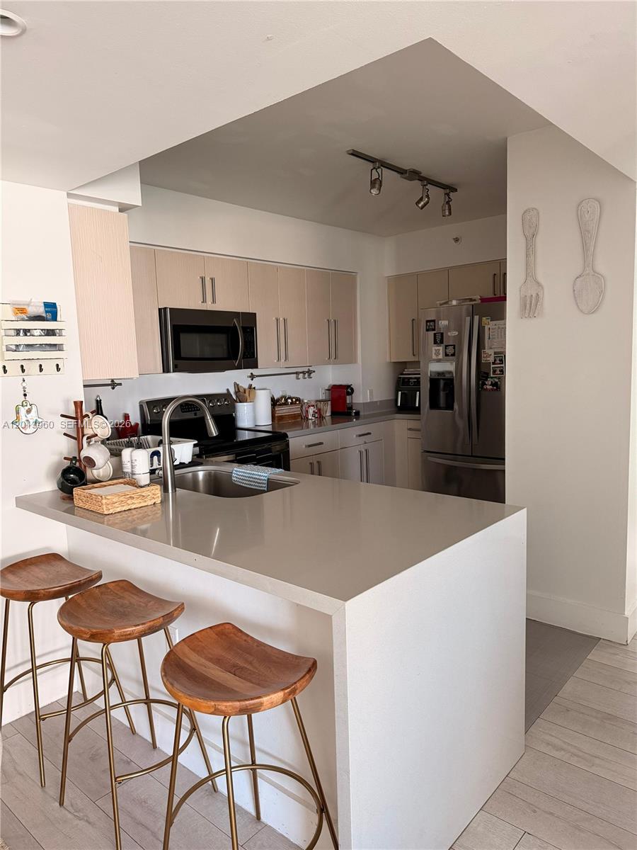 A kitchen features light wood cabinets, stainless steel appliances, and a quartz-topped breakfast bar — 1155 Brickell Bay Dr # 2904, Miami FL 33131, MIAMI, FL