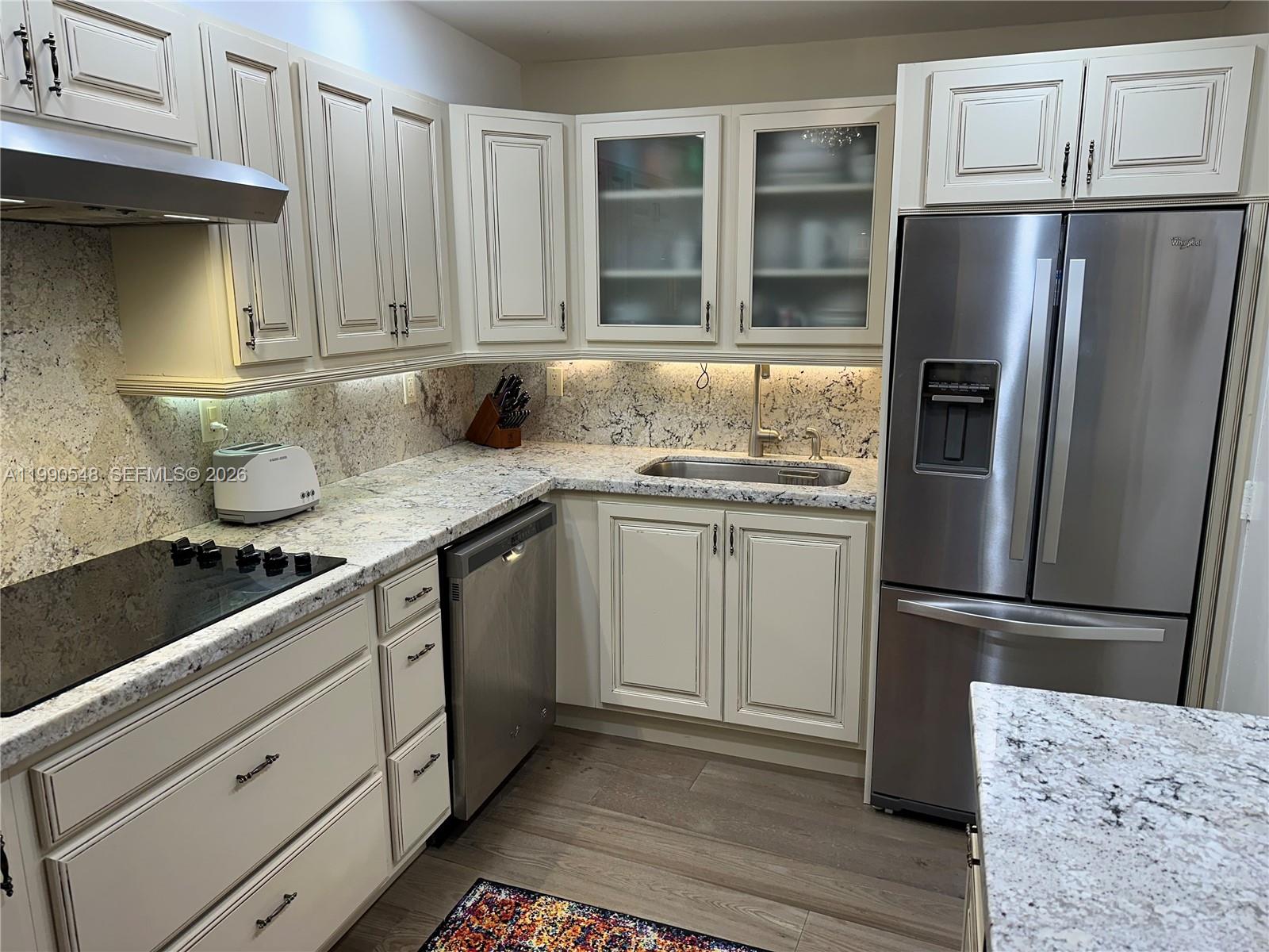 A kitchen features off-white cabinetry, stainless steel appliances, and speckled granite countertops — 6039 Collins Ave # 1431, Miami Beach FL 33140, MIAMI BEACH, FL