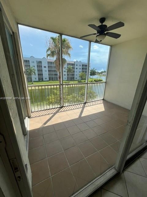 A screened-in balcony with tiled flooring, a ceiling fan, and a view of a lake — 10720 NW 66th St # 305, Doral FL 33178, DORAL, FL