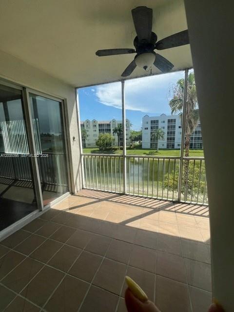 A tiled balcony with a ceiling fan overlooks a lake and apartment buildings — 10720 NW 66th St # 305, Doral FL 33178, DORAL, FL