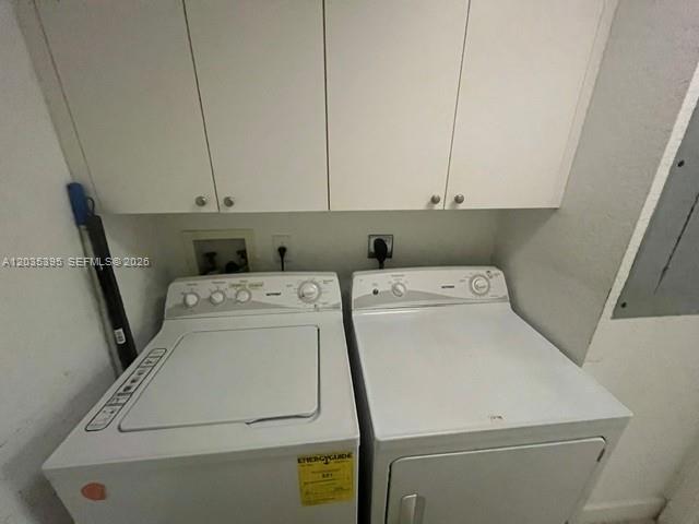 A laundry room featuring a white top-load washer and dryer beneath wall-mounted cabinets — 10720 NW 66th St # 305, Doral FL 33178, DORAL, FL
