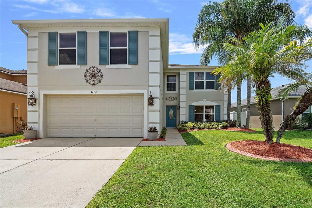 A two-story suburban house features a two-car garage, blue shutters, and a front palm tree — 1424 AGUACATE COURT, ORLANDO, FL