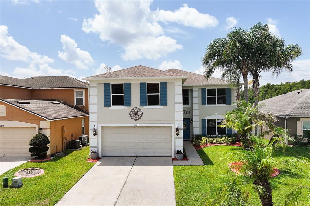 A two-story suburban house with a beige exterior, blue shutters, and a two-car garage — 1424 AGUACATE COURT, ORLANDO, FL