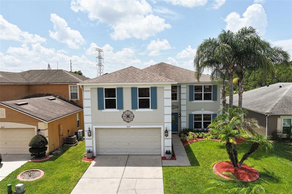 A two-story suburban house with a beige exterior, blue shutters, and a two-car garage — 1424 AGUACATE COURT, ORLANDO, FL