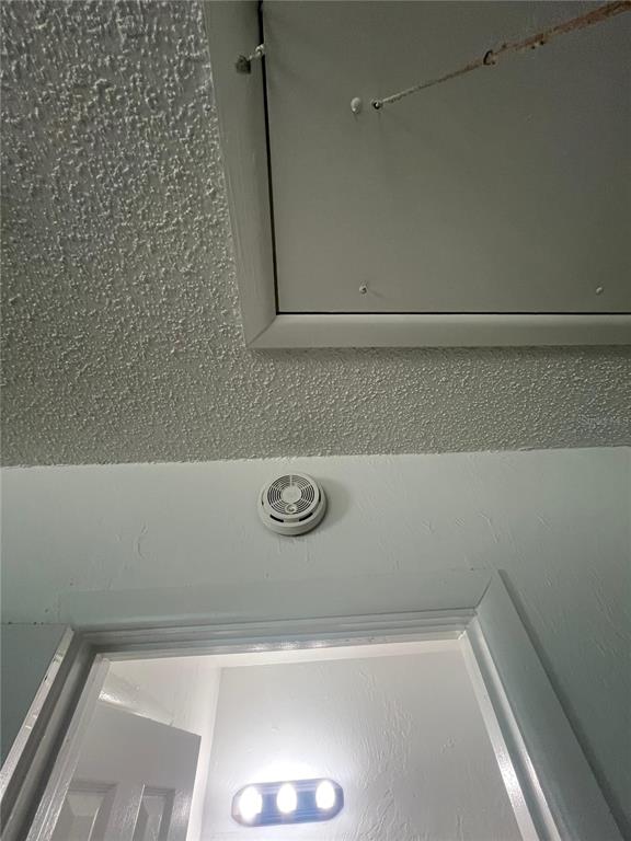 A smoke detector is mounted on the wall below a ceiling attic access panel — 2227 NOTTINGHAM ROAD, SOUTH DAYTONA, FL
