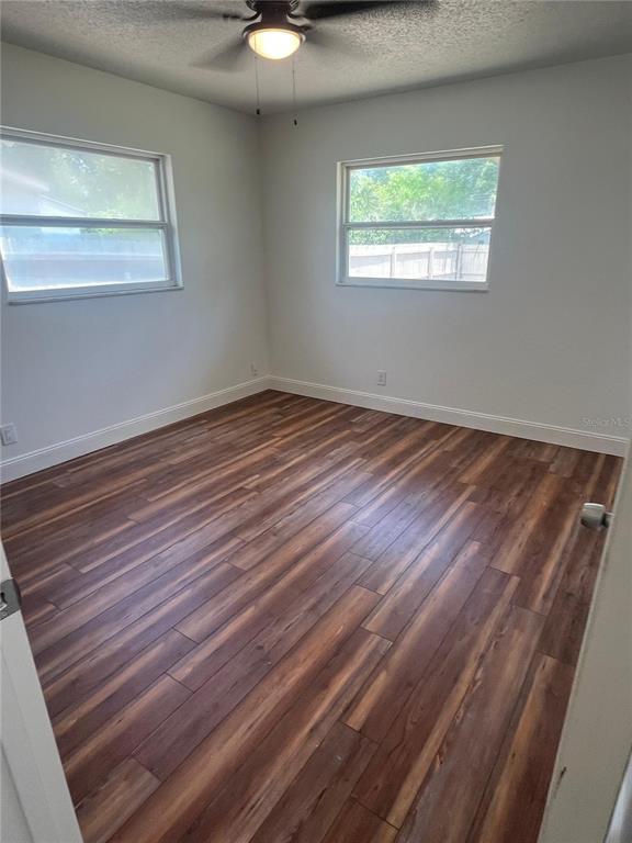 An empty bedroom features wood-look flooring, white walls, two windows, and a ceiling fan — 2227 NOTTINGHAM ROAD, SOUTH DAYTONA, FL