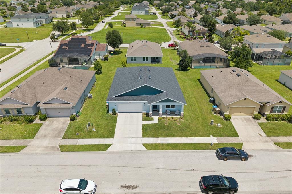 An aerial view shows a suburban neighborhood with single-family homes, paved streets, and green lawns — 4902 PALL MALL STREET E, KISSIMMEE, FL