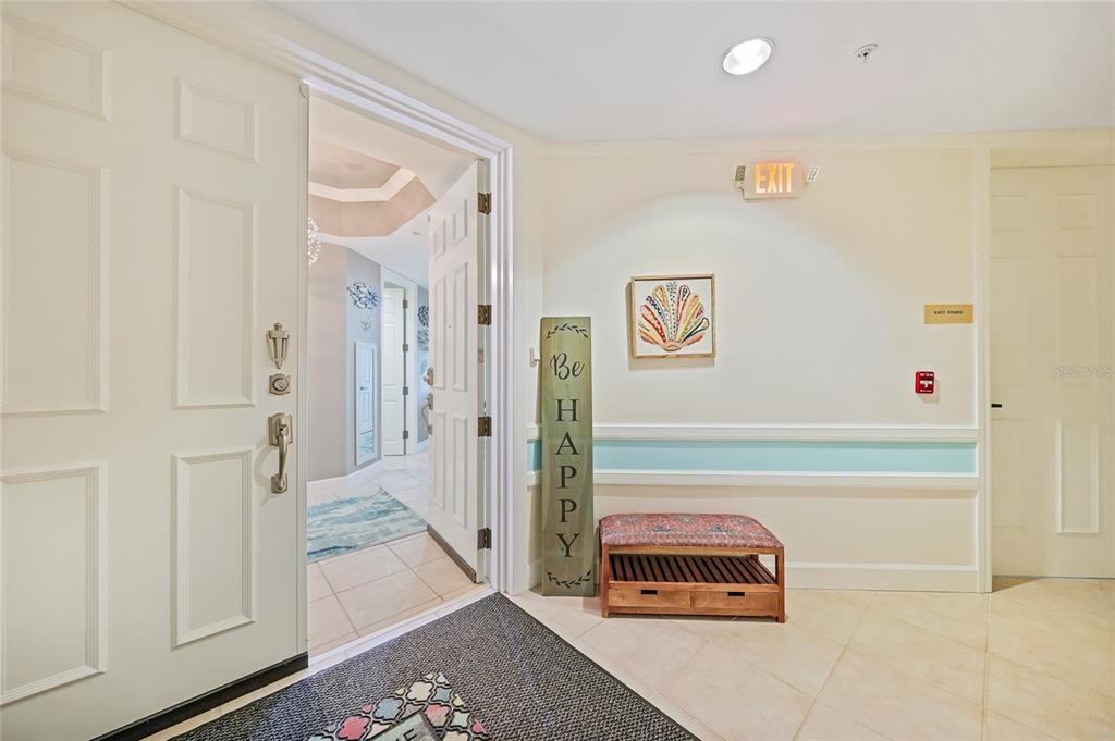 An interior hallway features a white door, a wooden bench, and a decorative sign — 2590 N BEACH ROAD UNIT 5, ENGLEWOOD, FL