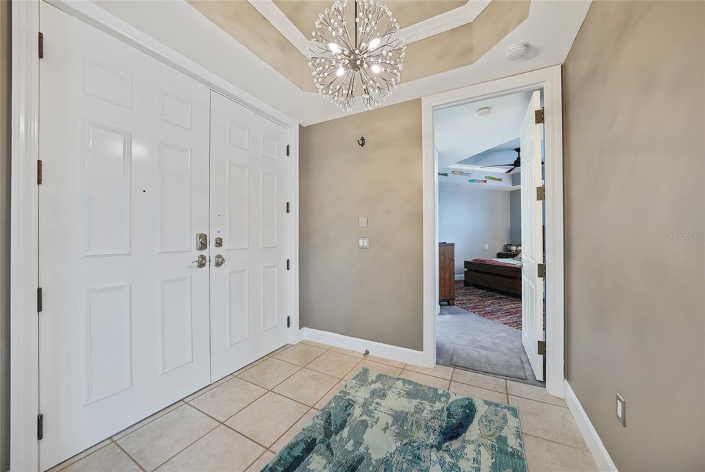 A foyer with tile flooring, a modern chandelier, and a doorway leading to a bedroom — 2590 N BEACH ROAD UNIT 5, ENGLEWOOD, FL
