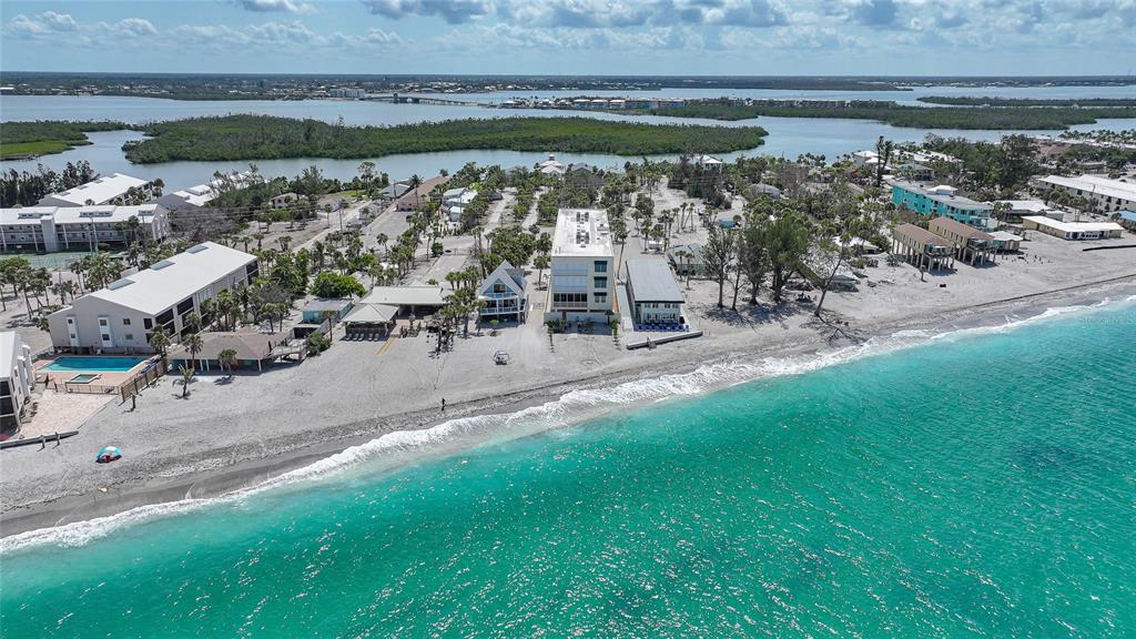 An aerial view shows a coastal property with several buildings situated along a sandy beach — 2590 N BEACH ROAD UNIT 5, ENGLEWOOD, FL