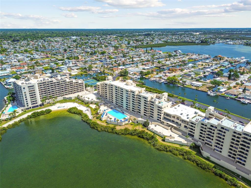 An aerial view shows a large apartment complex situated on a waterfront with a pool — 6009 SEA RANCH DRIVE UNIT 107, HUDSON, FL