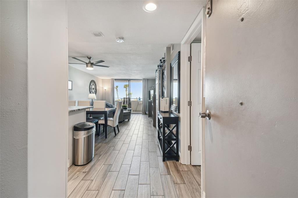 A view from an entryway into a living area with wood-look tile flooring and balcony — 6009 SEA RANCH DRIVE UNIT 107, HUDSON, FL