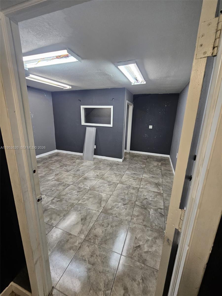 A small room features dark gray walls, a rectangular window, and light-colored tiled flooring — 6175 NW 167th St # G18, Hialeah FL 33015, HIALEAH, FL