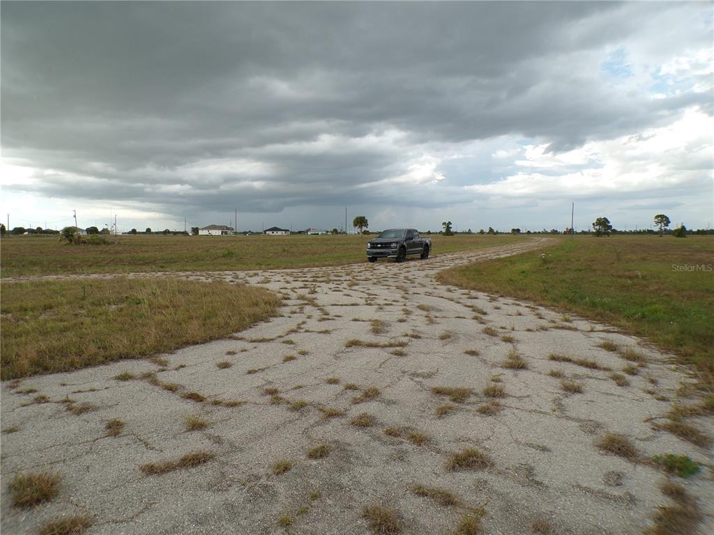 A dark pickup truck sits on a cracked, paved road in a large, open field — 1 BOBOLINK PLACE, PLACIDA, FL