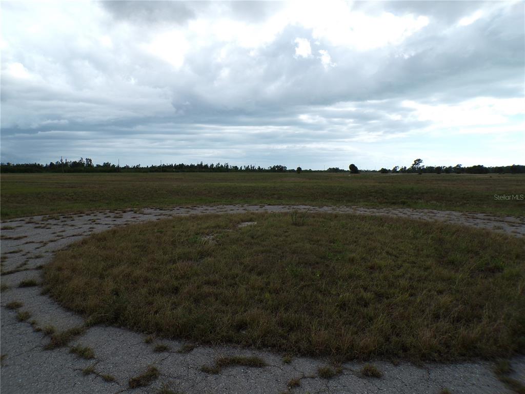 A large, flat, grassy field features a circular paved area in the foreground — 1 BOBOLINK PLACE, PLACIDA, FL