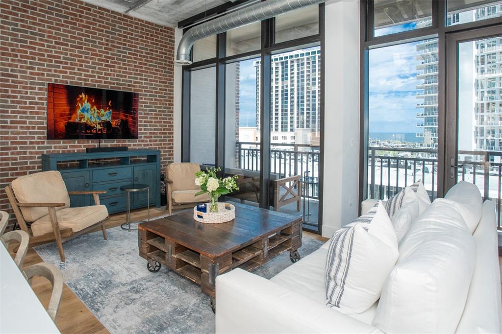 A living room features a brick wall, a pallet coffee table, and floor-to-ceiling windows — 175 2ND STREET S UNIT 808, ST PETERSBURG, FL