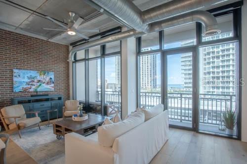 A living room features a brick wall, exposed ductwork, a white sofa, and floor-to-ceiling windows — 175 2ND STREET S UNIT 808, ST PETERSBURG, FL