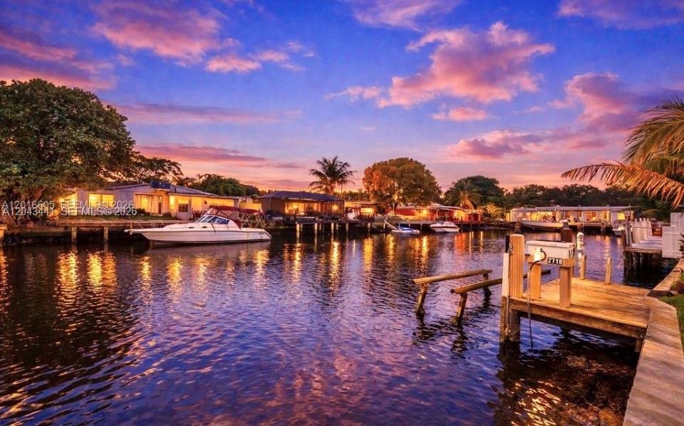 A waterfront view of a canal with a boat docked near houses at sunset — 2718 Sherman St, Hollywood FL 33020, HOLLYWOOD, FL