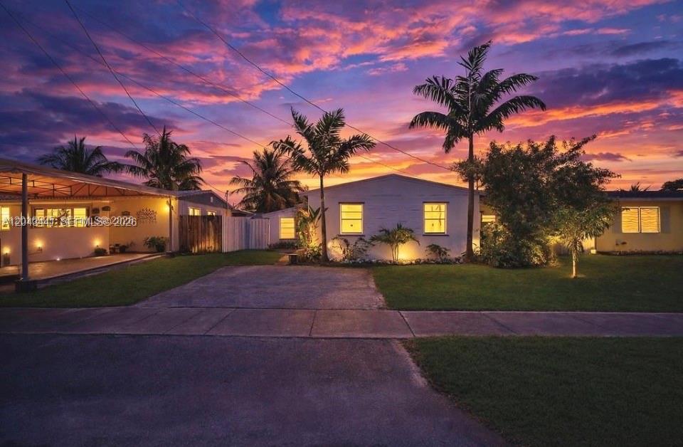 A single-story house with a driveway and palm trees under a vibrant sunset sky — 2718 Sherman St, Hollywood FL 33020, HOLLYWOOD, FL