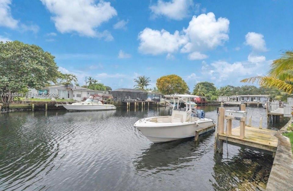 A boat is docked at a wooden pier on a canal in front of houses — 2718 Sherman St, Hollywood FL 33020, HOLLYWOOD, FL