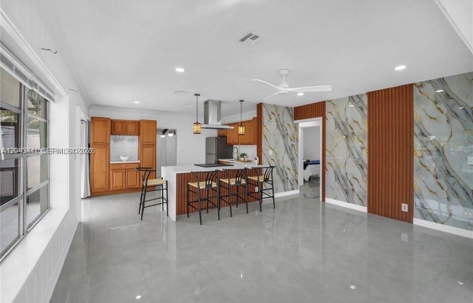 A kitchen with wood cabinets, a central island, and marble-patterned accent walls — 2718 Sherman St, Hollywood FL 33020, HOLLYWOOD, FL