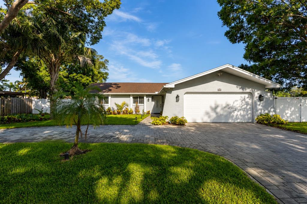A single-story house with a paved driveway, a two-car garage, and mature trees — 3276 FOX HILL DRIVE, CLEARWATER, FL