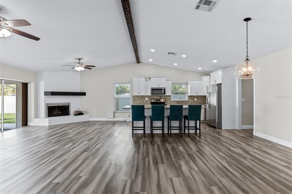 An open-concept kitchen and living area featuring a white brick fireplace and wood-look flooring — 3276 FOX HILL DRIVE, CLEARWATER, FL