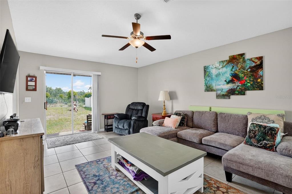 A living room features a sectional sofa, a coffee table, and a sliding glass door — 4507 ETERNAL PRINCE DRIVE, SUN CITY CENTER, FL