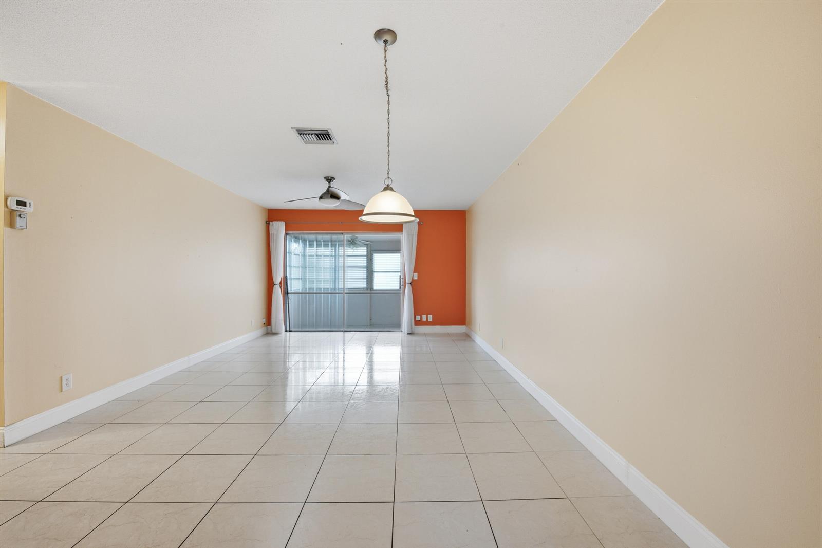 An empty room with beige walls, a bright orange accent wall, and tiled flooring — 2789 Ashley Drive W # C, West Palm Beach FL 33415, WEST PALM BEACH, FL
