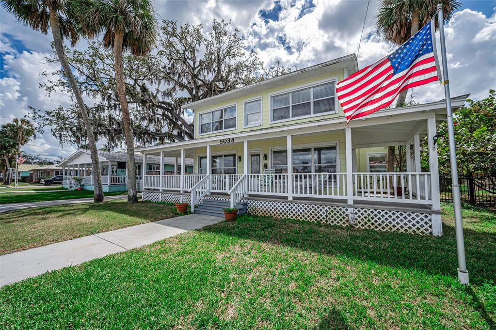 A yellow two-story house with a wrap-around porch, brick chimney, and a golf cart parked outside — 5038 SUNSET BOULEVARD, PORT RICHEY, FL