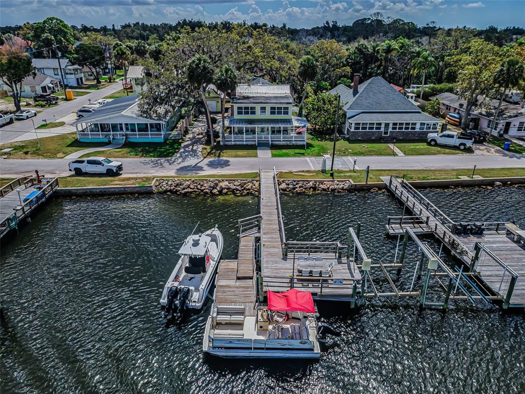 A two-story yellow house with a wrap-around porch and an American flag on a pole — 5038 SUNSET BOULEVARD, PORT RICHEY, FL