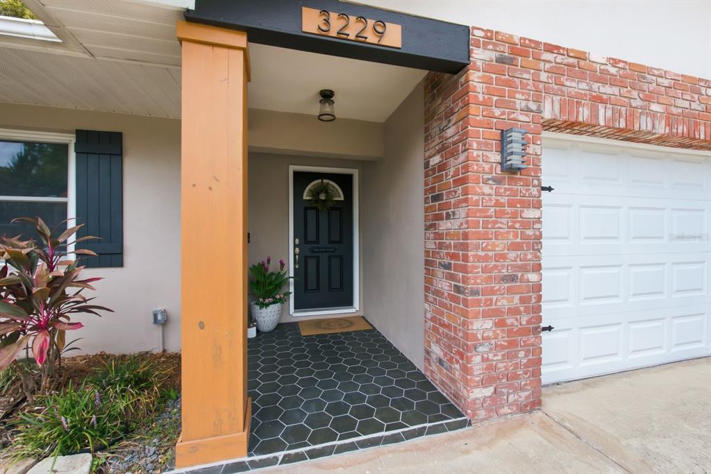The exterior entrance features a dark front door, hexagonal floor tiles, and a brick facade — 3229 SPANISH MOSS LANE, PALM HARBOR, FL