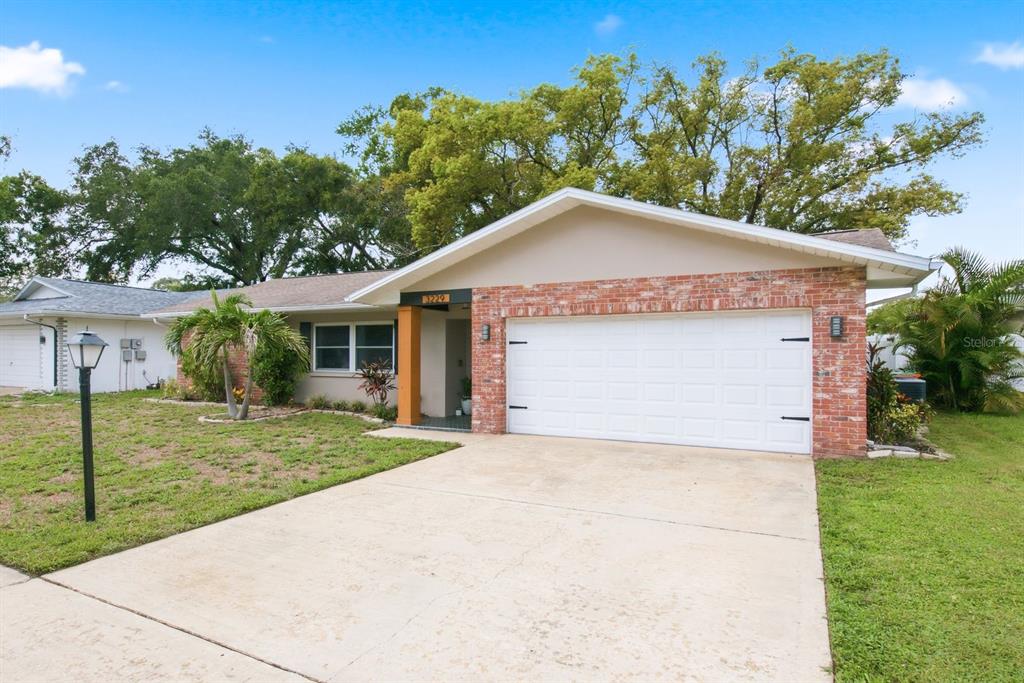 A single-story house with a brick facade, a two-car garage, and a concrete driveway — 3229 SPANISH MOSS LANE, PALM HARBOR, FL