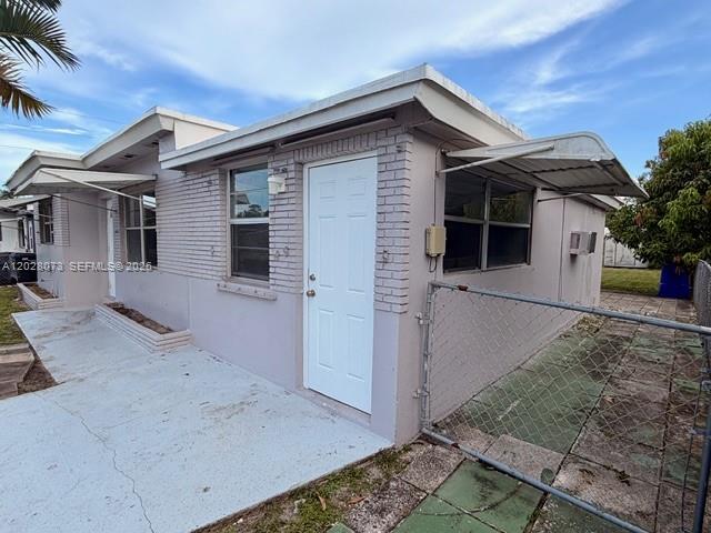 The exterior of a light-colored, single-story building features a white door and metal awnings — 5608 Garfield St, Hollywood FL 33021, HOLLYWOOD, FL